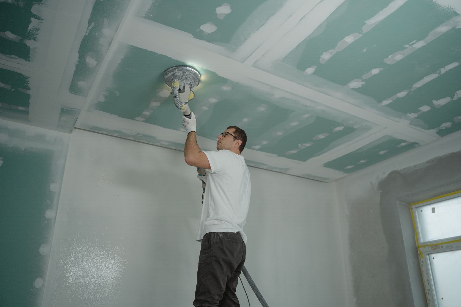 Drywall ceiling sanding before paint (stock image)